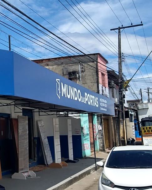 Fachada da loja Mundo das Portas no Novo Aleixo, com o letreiro azul e portas expostas na calçada